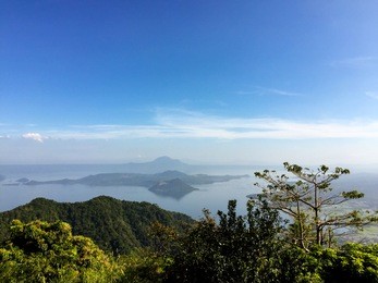 taal volcano (bulkang taal) on volcano island in the middle of taal lake in tagaytay, luzon, philippines on a clear afternoon. picturesque panoramic view with hills and forest in the foreground.