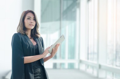 beautiful asian businesswoman wearing black suit jacket using tablet computer in office ,working by technology concept.