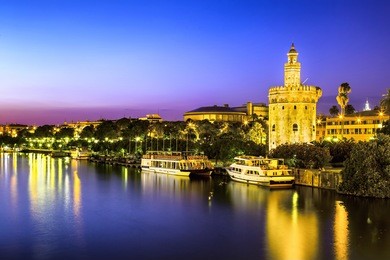 view of golden tower (torre del oro) of seville, andalusia, spain over river guadalquivir at sunset