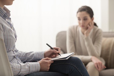psychologist listening to her patient and writing down notes, mental health and counseling concept