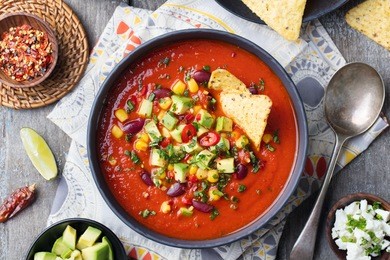 mexican tomato, bean, bell pepper soup in black bowl. top view
