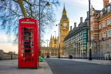london, england - the iconic british old red telephone box with the big ben at background in the center of london