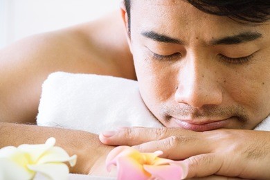 man is relaxing in day spa. he is having a massage.