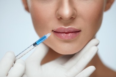 lip augmentation. beautiful young woman's mouth receiving hyaluronic acid injection. closeup of beautician hands doing beauty procedure to sexy female lips. cosmetology treatment. high resolution