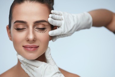 facial treatment. portrait of beautiful sexy woman with closed eyes and black surgical lines on skin. closeup of hands touching young female face. plastic surgery concept. high resolution