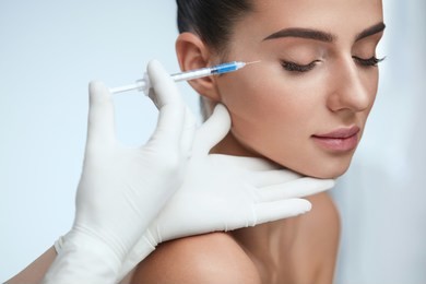 cosmetic treatment. closeup beautician hands doing facial skin lifting injection to woman's face. beautiful female with closed eyes receiving beauty procedure indoors. plastic surgery. high resolution