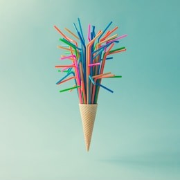 ice cream cone with colorful drinking straws on bright blue background. minimal food concept.