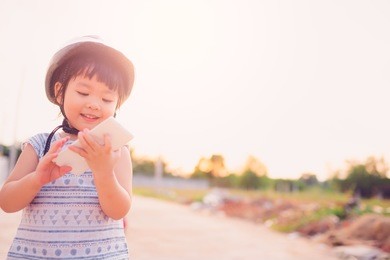child girl wear helmet on street and happy look smart phone.asian child.child development.technology concept.insurance concept.