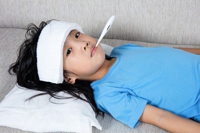 asian chinese little girl getting measurement for fever temperature at home.