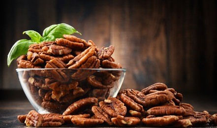bowl with pecan nuts on wooden table. delicacies