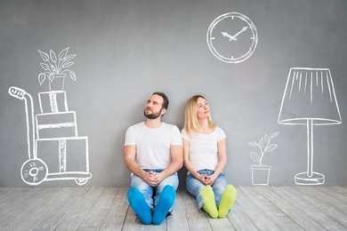 happy couple sitting on wooden floor. moving house day, new home and design interior concept