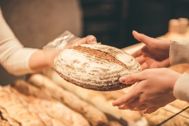 cropped image of woman choosing bread while doing shopping in supermarket