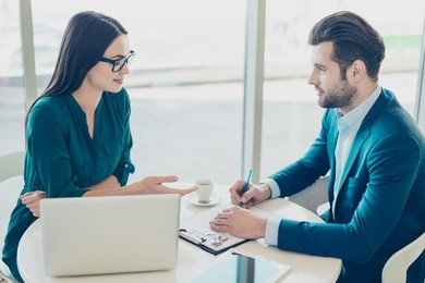 photo of young man talking to broker and putting a signature on contract.