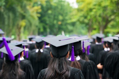 back of graduates during commencement at university. close up at graduate cap. 