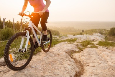 girl on mountain bike rides on the trail on a beautiful sunrise