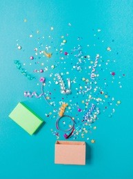 pink gift box with various party confetti, streamers, noisemakers and decoration on a blue background. colorful celebration concept.