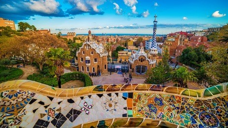 barcelona, catalonia, spain: the park guell of antoni gaudi at sunset. the two buildings at the entrance of the park and gaudi's mosaic work on the main terrace.
