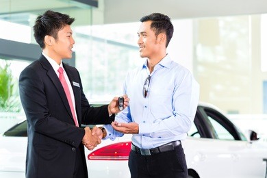 asian car salesman selling auto to customer