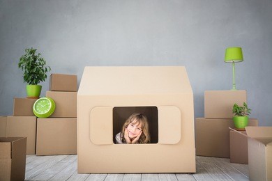 happy child playing into new home. moving house day and real estate concept