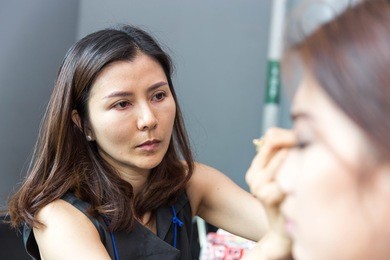 makeup artist is making up model for show/ young  thailand woman applying make up by make-up artist
