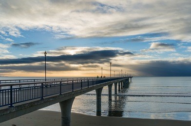 new brighton pier on sunrise with dramatic clouds. christchurch, new zealand