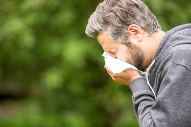 man with allergy or an infection sneezing 