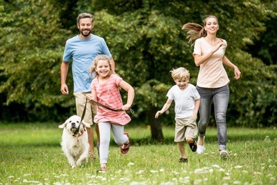 happy children and parents with dog as family running in the nature