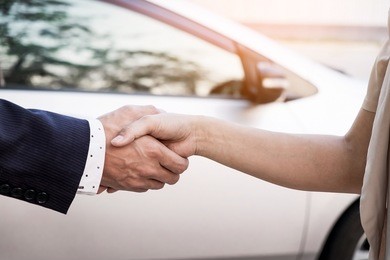 close-up image of a firm handshake after a successful deal of buying a car.