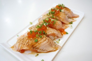 closeup of salmon sushi on a white plate with salmon roe and