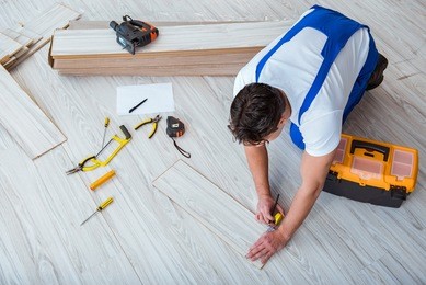 repairman laying laminate flooring at home