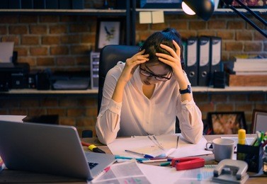 asian women are stressed out of work. she is in the office at night