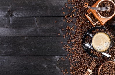 coffee background, top view with copy space. black cup of coffee, ground coffee, mill, bowl of roasted coffee beans on dark wooden background