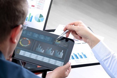 business colleagues working and analyzing financial figures on a digital tablet