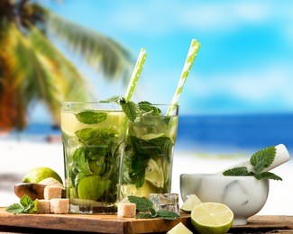mohito lime drinks on wooden with blur beach background. fresh drinks with fruits on wood. summer concept. 