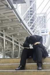businessman sitting clasping the head show stress in modern cities