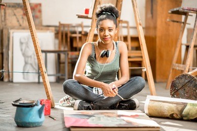 beautiful african ethnicity student painting on the floor at the university classroom