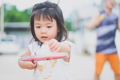 little asian girl playing badminton with her father in front of the house.