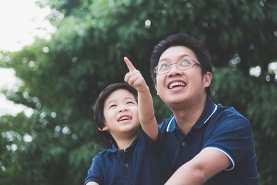 portrait of asian father and son looking up outdoors