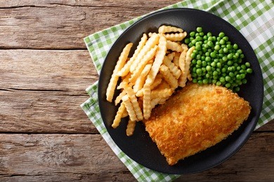 traditional british food: fish and chips with green peas close-up on a plate on a table. horizontal view from above
