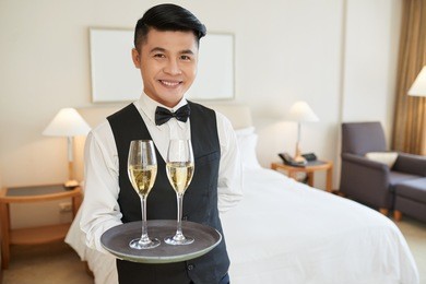 smiling handsome waiter with two glasses of champagne