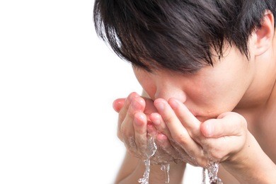 man washing face in bathroom sink