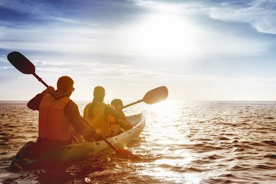 kayaking concept with family of father mother and son swimming at sea at sunset time. space for text
