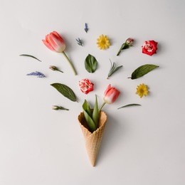 ice cream cone with colorful flowers on white background. flat lay. minimal summer concept.
