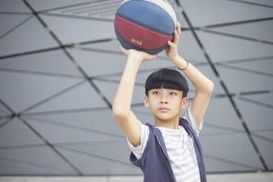 portrait of cool asian kid holding basketball aiming & shooting
