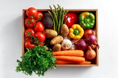 fresh vegetables in wooden box on white wooden background