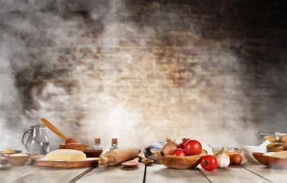 baking ingredients placed on wooden table, ready for cooking pizza. copyspace for text. concept of food preparation, brick wall on background.