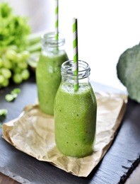 green smoothie, healthy, organic drinks with fresh vegetables and fruits. two smoothie glasses with drinking straw on a slate plate. close-up shot.