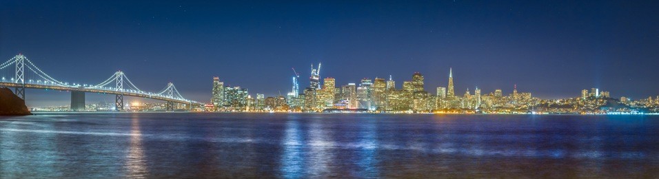 classic panoramic view of the skyline of san francisco with famous oakland bay bridge  illuminated in beautiful twilight after sunset in summer, california, usa
