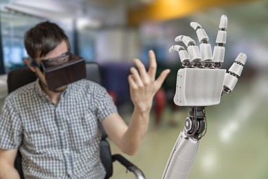 young man is controlling robotic hand with virtual reality headset.