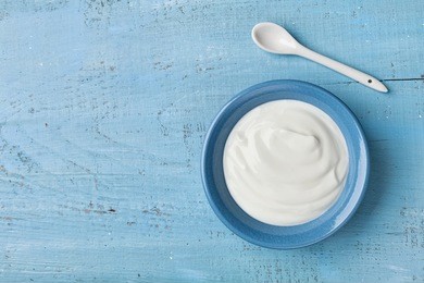 greek yogurt in blue bowl on rustic wooden table top view.